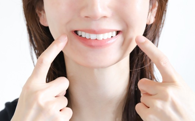 白い歯を指さす女性